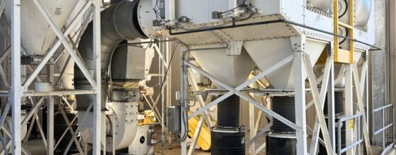 Outdoor baghouse dust collectors connected by ducts for air pollution control at a plant